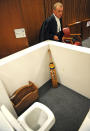 State prosecutor Gerrie Nel, alongside a reconstruction of a toilet cubicle, in court Monday, April 14, 2014, through which Oscar Pistorius shot and killed his girlfriend, Reeva Steenkamp on St. Valentine's day in 2013. The judge temporarily adjourned the murder trial of Pistorius after the athlete started to sob while testifying about the moments before he killed Steenkamp. (AP Photo/Antoine de Ras, Pool)