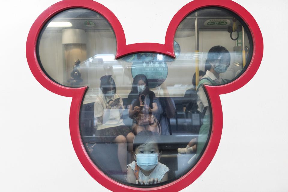 This image shows a child peering through a window shaped like Mickey Mouse.