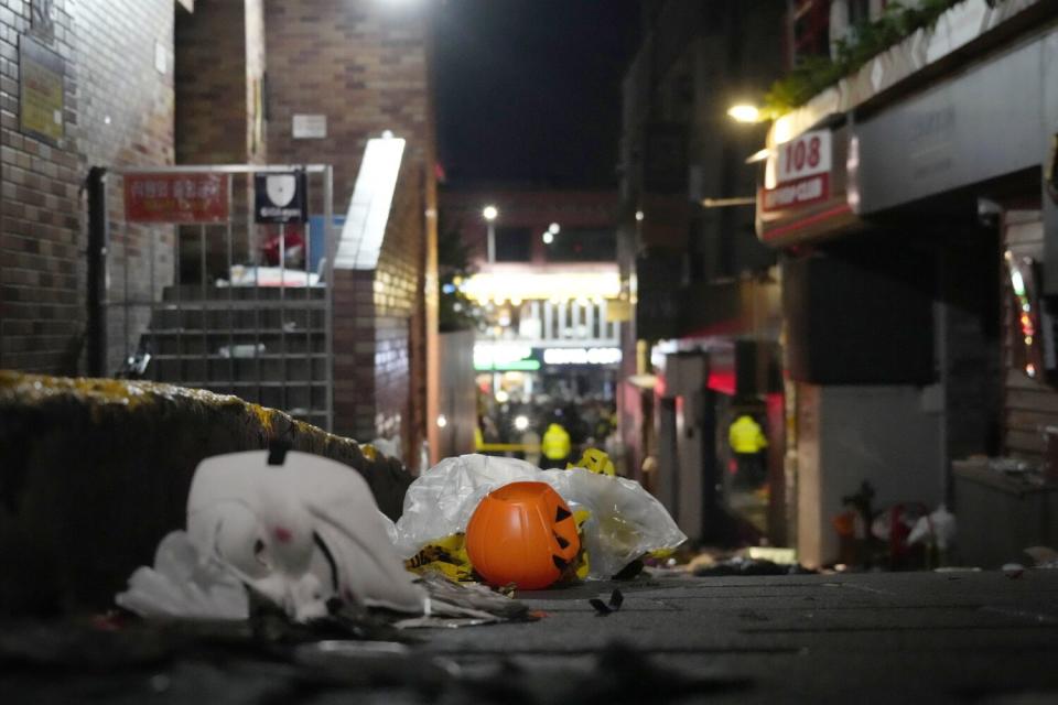 A jack-o'-lantern sits with other debris in an alley