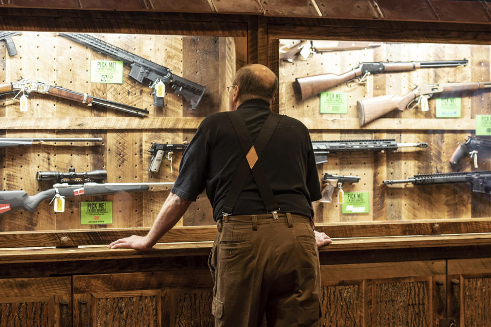 FILE - In this April 25, 2019, file photo, a man looks at cases of firearms in the halls of the Indianapolis Convention Center where the National Rifle Association will be holding its 148th annual meeting in Indianapolis. The number of background checks conducted by federal authorities is on pace to break a record by the end of this year. (AP Photo/Lisa Marie Pane, File)