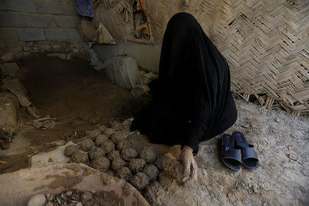 A woman makes ''turba'', a piece of stone or molded clay made of local soil, at her home in Kerbala, Iraq April 2, 2018. Picture taken April 2, 2018. REUTERS/Alaa Al-Marjani