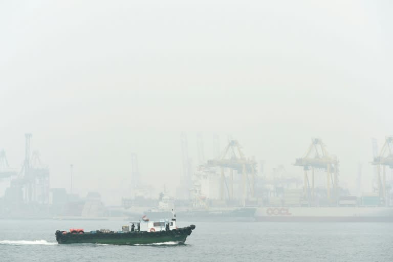 A boat sails past Keppel container port terminal blanketed with thick smog in Singapore on September 24, 2015