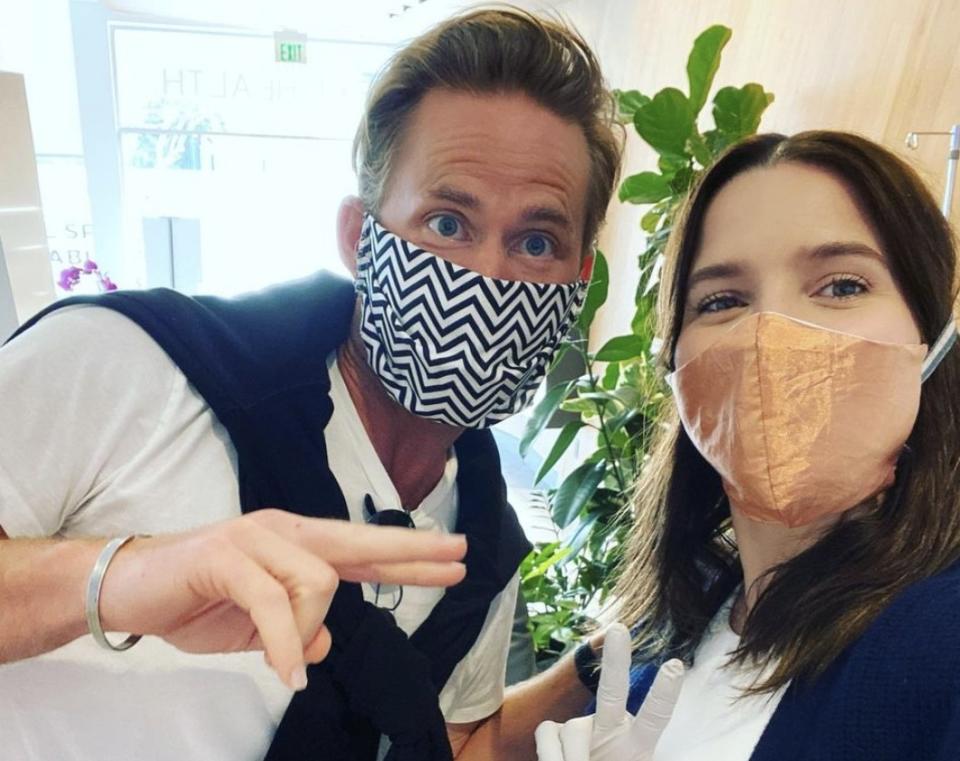 Sophia and Grant pose while wearing masks in a COVID test center