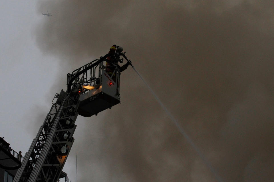 <p>Firefighters spray on fire from above as a helicopter flies even higher above at Tsukiji Fish Market on Thursday, Aug. 3, 2017, in Tokyo. (Photo: Sherry Zheng/AP) </p>