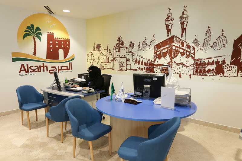 Employees sit behind their desks, as they wait for customers at a travel agency in Riyadh