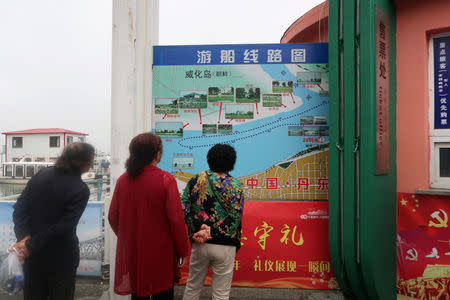 Chinese tourists look at a map detailing the route of a boat tour on the Yalu River, which separates North Korea and China, at a ticket office in Dandong, Liaoning province, China June 7, 2018. REUTERS/Brenda Goh