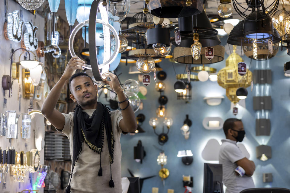 A salesman adjusts lighting fixtures for sale at an electrical shop in the capital Addis Ababa, Ethiopia Tuesday, July 21, 2020. Ethiopia's prime minister said Tuesday his country, Egypt and Sudan have reached a "major common understanding which paves the way for a breakthrough agreement" on a massive hydroelectric dam project that Ethiopia says offers a critical opportunity to pull millions of its nearly 110 million citizens out of poverty and become a major power exporter but which has led to sharp regional tensions. (AP Photo/Mulugeta Ayene)