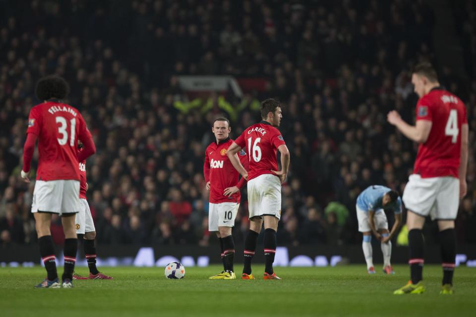 Manchester United's Wayne Rooney, center, and Michael Carrick, center right, wait with teammates for play to begin after a second goal by Manchester City's Edin Dzeko, out of frame, during their English Premier League soccer match at Old Trafford Stadium, Manchester, England, Tuesday March 25, 2014. (AP Photo/Jon Super)