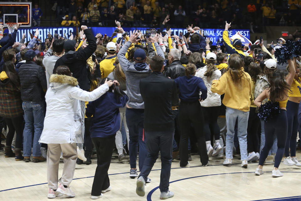 West Virginia fans run onto the court after a defeating Kansas in an NCAA college basketball game on Saturday, Jan. 20, 2024, in Morgantown, W.Va. (AP Photo/Kathleen Batten)