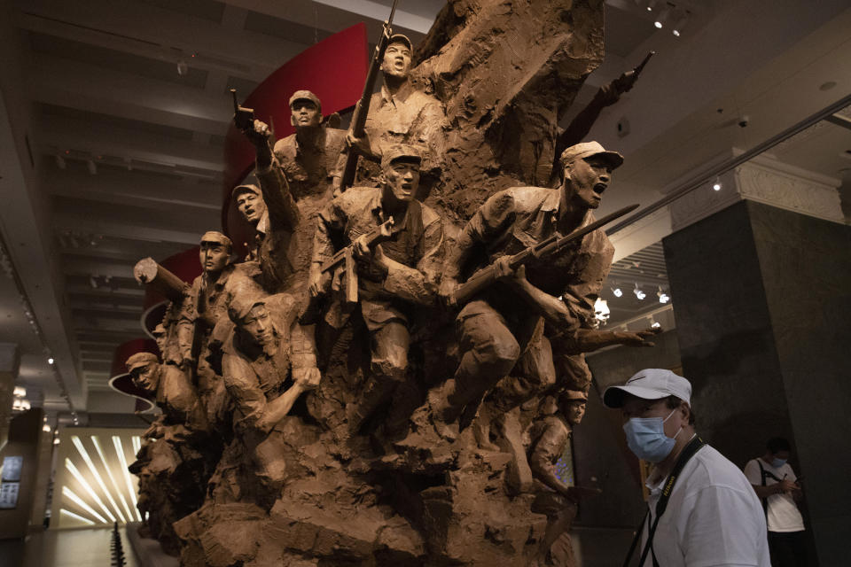 A visitor wearing mask to protect from the coronavirus walks past a sculpture depicting Chinese soldiers at an exhibition that included the War of Resistance against Japanese Aggression in Beijing on Thursday, Sept. 3, 2020. China on Thursday commemorated the 75th anniversary of the end of World War II in the Pacific, during which it endured a brutal invasion and occupation of much of its territory by Japan. (AP Photo/Ng Han Guan)