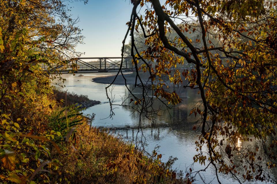 The sun rises over the Raccoon River lighting the fall colors in Waterworks Park, Friday, Oct. 20, 2023.