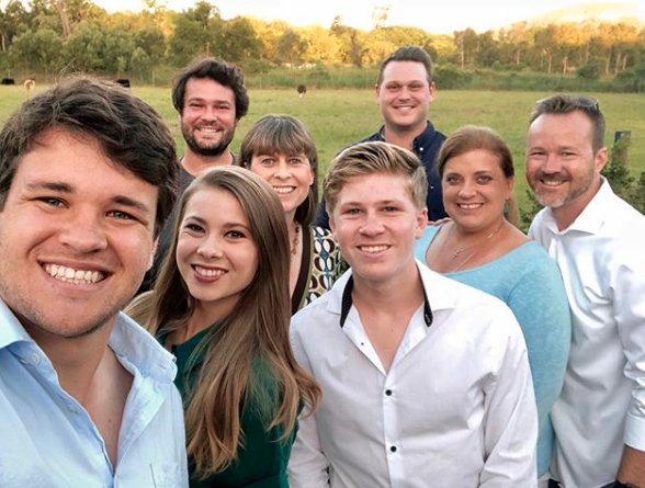 Bindi Irwin and Chandler Powell with Robert and Terri Irwin and Chandler's parents Shannan and Chris Powell pose in the Australian bush in smart casual wear