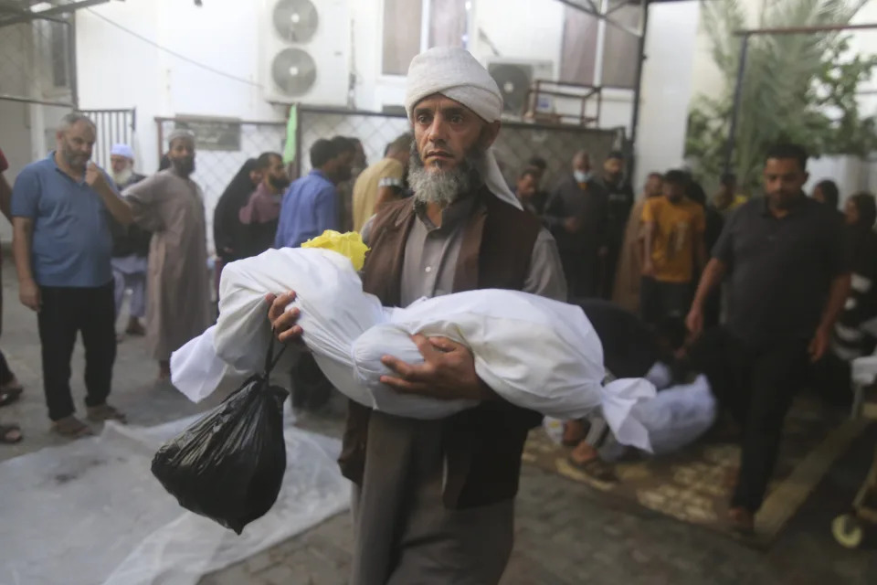 A Palestinian carries a child killed in the Israeli bombardment of the Gaza Strip in Rafah on Sunday, Oct. 22, 2023. (AP Photo/Hatem Ali)