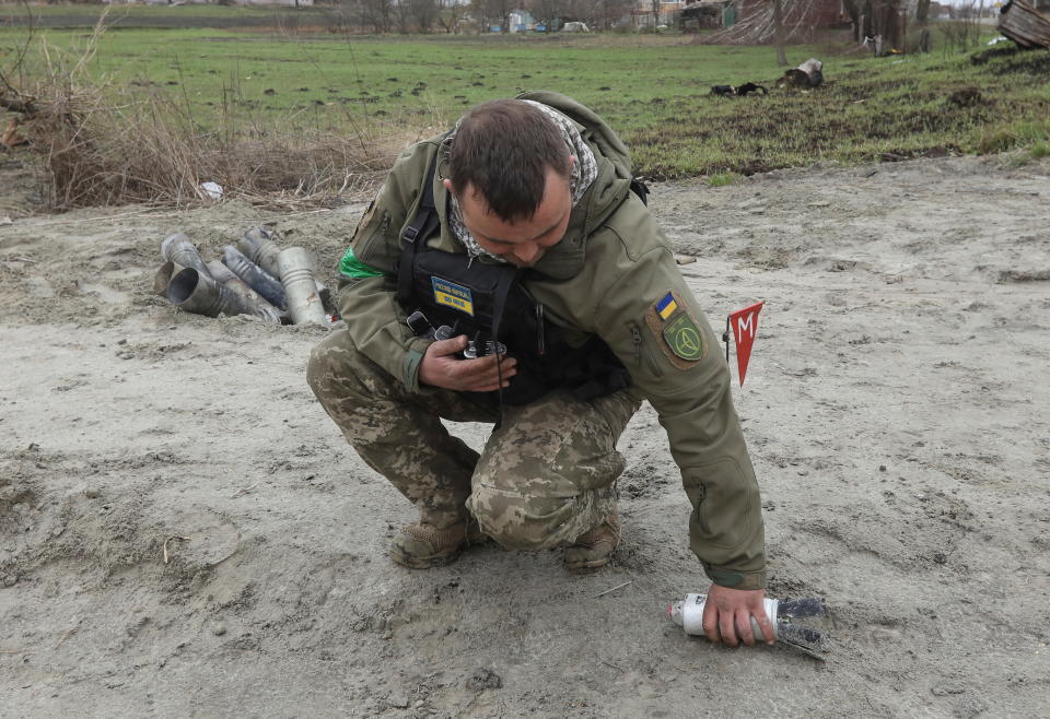 A military specialist picks up an unexploded part of a cluster bomb.