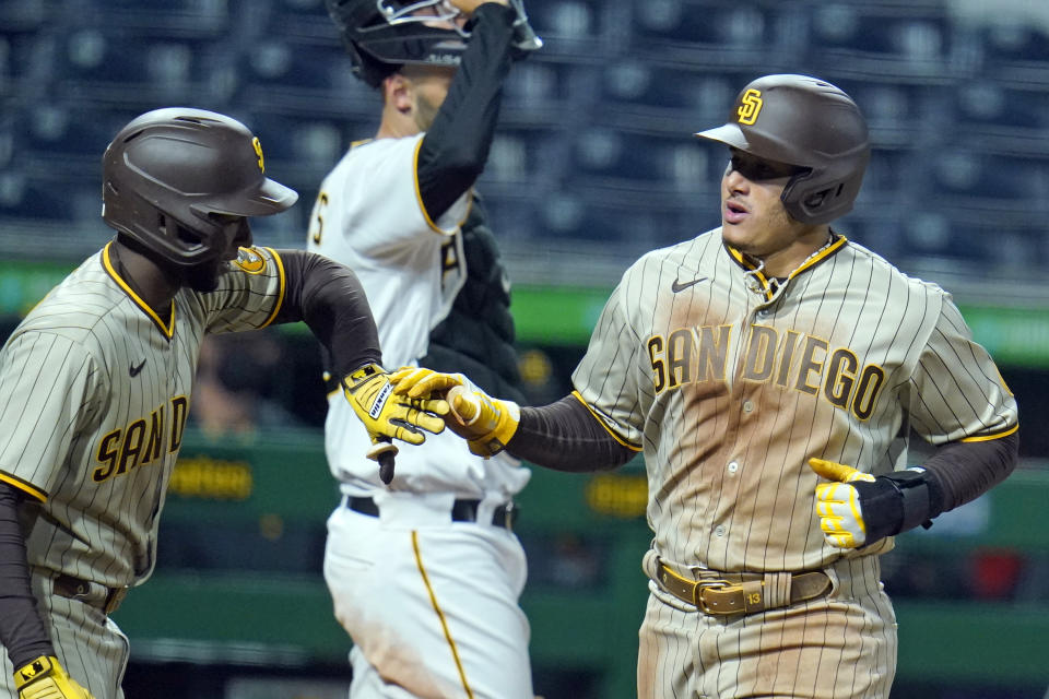 San Diego Padres' Manny Machado, right, is greeted by Jurickson Profar, left, after they both scored on a single by Wil Myers off Pittsburgh Pirates starting pitcher Luis Oviedo during the seventh inning of a baseball game in Pittsburgh, Monday, April 12, 2021. (AP Photo/Gene J. Puskar)