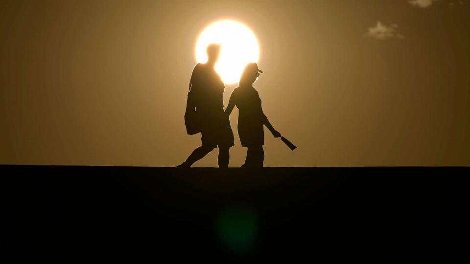 PHOTO: People walk along a trail as the sun sets, July 16, 2023, in Death Valley National Park, Calif. (John Locher/AP)