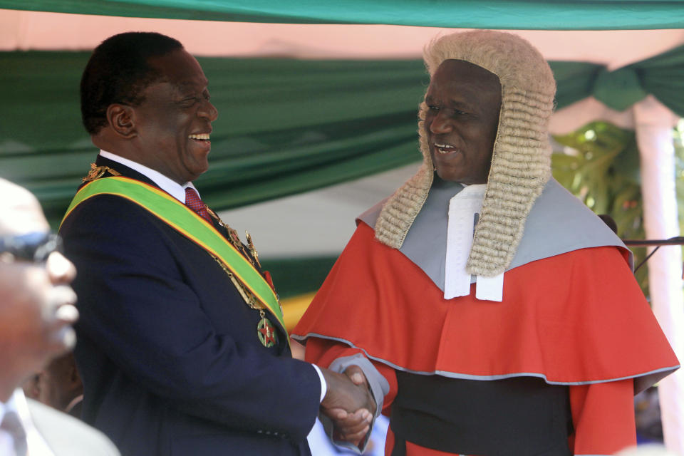Zimbabwean President Emmerson Mnangagwa,left, is congratulated by Chief Justice Luke Malaba after taking his oath during his inauguration ceremony at the National Sports Stadium in Harare, Sunday, Aug. 26, 2018. The Constitutional Court upheld Mnangagwa's narrow election win Friday, saying the opposition did not provide " sufficient and credible evidence" to back vote- rigging claims.(AP Photo/Tsvangirayi Mukwazhi)