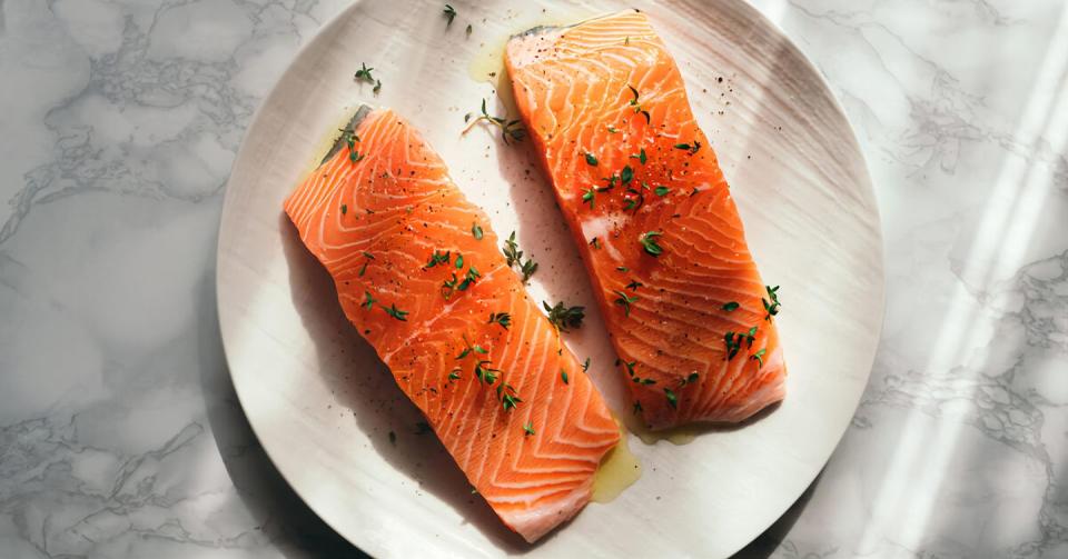 high angle view of salmon slice with herbs on plate on table