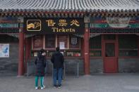 People stand in front of the closed tickets office to the Juyongguan section of the Great Wall, where a notice is seen saying that the place is closed to visitors for the safety concern following the outbreak of a new coronavirus, near Beijing