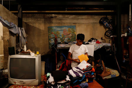 A youth folds his clothes inside a flat on the ground floor of an apartment block in downtown in Caracas, Venezuela, March 19, 2019. REUTERS/Carlos Jasso