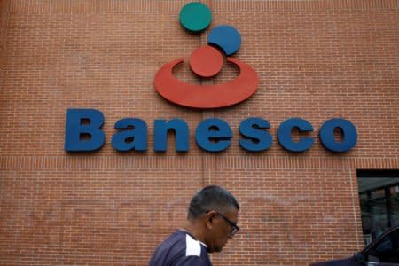A man walks past the corporate logo of Banesco bank at one of its branches in Caracas, Venezuela May 3, 2018. REUTERS/Carlos Garcia Rawlins