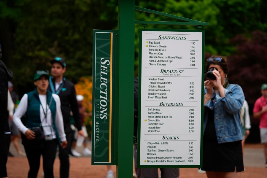 Patrons view the prices of food items on a board during a practice round in preparation for the Masters golf tournament at Augusta National Golf Club Tuesday, April 9, 2024, in Augusta, Ga. (AP Photo/Matt Slocum)