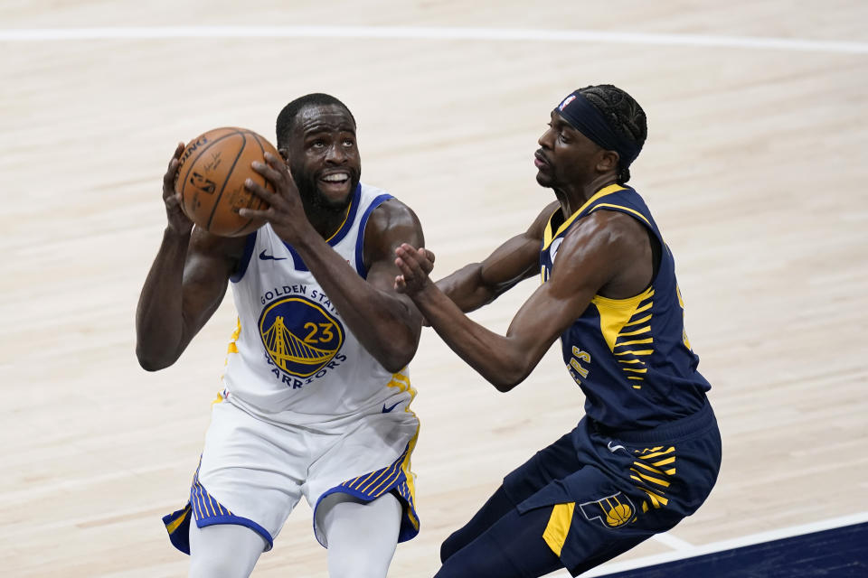 Golden State Warriors' Draymond Green (23) goes to the basket against Indiana Pacers' Justin Holiday during the second half of an NBA basketball game Wednesday, Feb. 24, 2021, in Indianapolis. (AP Photo/Darron Cummings)