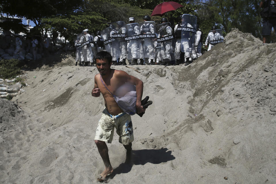 A Central American migrant who crossed the Suchiate River from Guatemala to Mexico is blocked by Mexican National Guards on the riverbank near Ciudad Hidalgo, Mexico, Monday, Jan. 20, 2020. More than a thousand Central American migrants hoping to reach United States marooned in Guatemala walked en masse across a river leading to Mexico in an attempt to convince authorities there to allow them passage through the country. (AP Photo/Marco Ugarte)