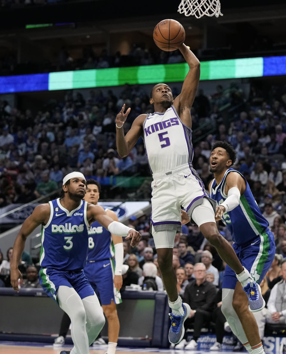 Sacramento Kings guard De'Aaron Fox (5) makes a move to the basket in front of Dallas Mavericks forward Christian Wood (35) and guard Jaden Hardy (3) during the first half of an NBA basketball game in Dallas, Wednesday, April 5, 2023. (AP Photo/Sam Hodde)