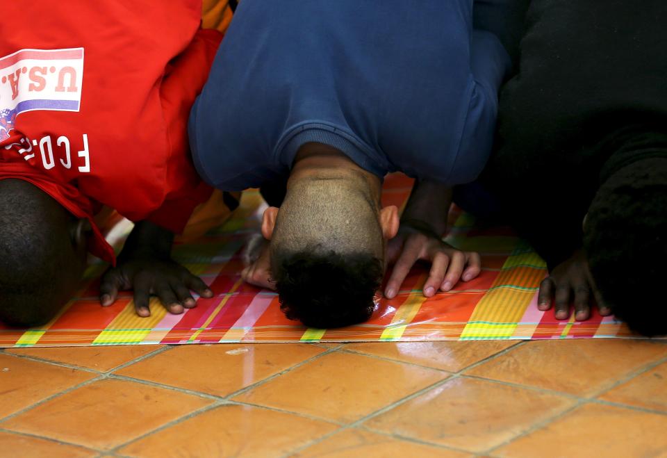 Adolescent migrants pray at an immigration centre in Caltagirone, Sicily March 18, 2015. The number of migrants reaching Italy by sea this year is set to top last year's record of 170,000, the International Organization for Migration (IOM) said. In the past week alone 10,000 have arrived. Another 400 people drowned before making it to Italy's shores, survivors said. The number of minors traveling alone in this mass migration has soared -- underage arrivals to Italy tripled in 2014 from the previous year. Picture taken March 18, 2015. To match Insight ITALY-MIGRANTS/BOYS REUTERS/Alessandro Bianchi