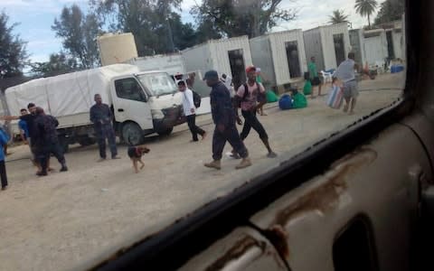 Papua New Guinea officials, wearing army fatigues, walk inside the closed detention centre on Manus Island - Credit: Reuters