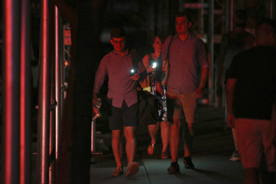 Commuters use their phones as flashlights during a widespread power outage, Saturday, July 13, 2019, in New York. Authorities were scrambling to restore electricity to Manhattan following a power outage that knocked out Times Square's towering electronic screens, darkened marquees in the theater district and left businesses without electricity, elevators stuck and subway cars stalled. (AP Photo/Michael Owens)