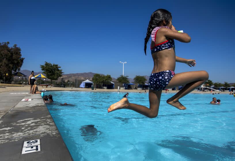 LAKE VIEW TERRACE, CA - JULY 11, 2022 - Emma Aguilar, 6, of Pacoima, CA leaps into the 1.5-acre swimming lake at the Hansen Dam Aquatic Center as temperatures reached 90 degrees in Lake View Terrace on July 11, 2022. The weather is expected to get hotter over the coming weekend. (Francine Orr/ Los Angeles Times)