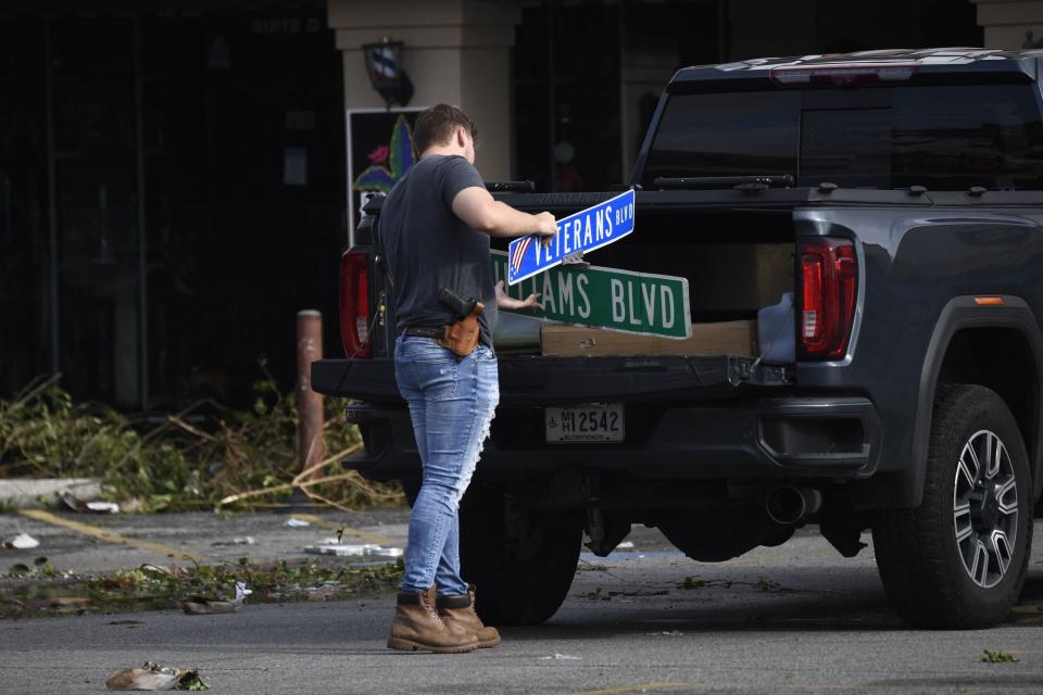 A man cleans up damaged street signs in Louisiana