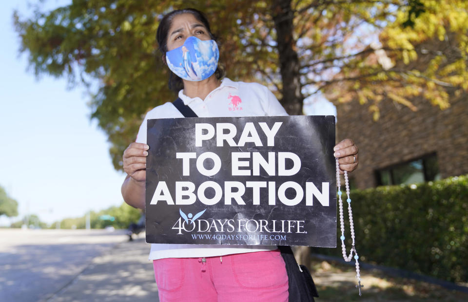 Maria Peña holds a rosary and sign out outside a building housing an abortion provider in Dallas, Thursday, Oct. 7, 2021. (AP Photo/LM Otero)