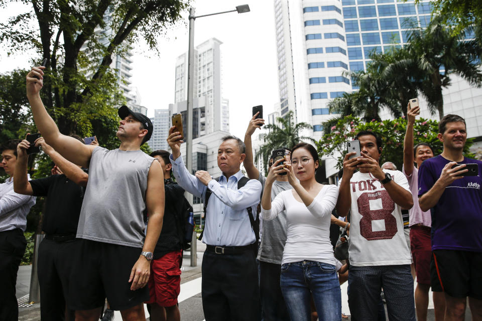 In this June 12, 2018, file photo, spectators take photos of the motorcade of North Korea leader Kim Jong Un as it leaves the St. Regis Hotel on the way to the Capella Hotel in Singapore where the summit between Kim and U.S. President Donald Trump is scheduled. Trump and Kim are planning a second summit in the Vietnam capital of Hanoi Feb. 27-28. (AP Photo/Yong Teck Lim, File)