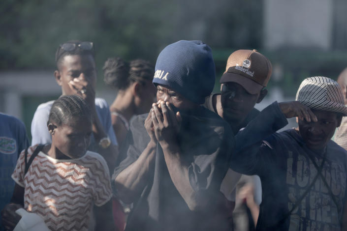 Bystanders look at the bodies of alleged gang members that were set on fire by a mob after they were stopped by police while traveling in a vehicle in the Canape Vert area of Port-au-Prince, Haiti, Monday, April 24, 2023. (AP Photo/Odelyn Joseph)