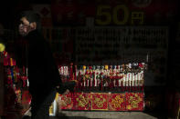 In this Feb. 13, 2020, photo, a man wearing a mask walks past a street kiosk selling souvenirs in Yokohama's Chinatown, near Tokyo. A top Olympic official made clear Friday the 2020 Games in Tokyo will not be cancelled despite the virus that has spread from China. (AP Photo/Jae C. Hong)