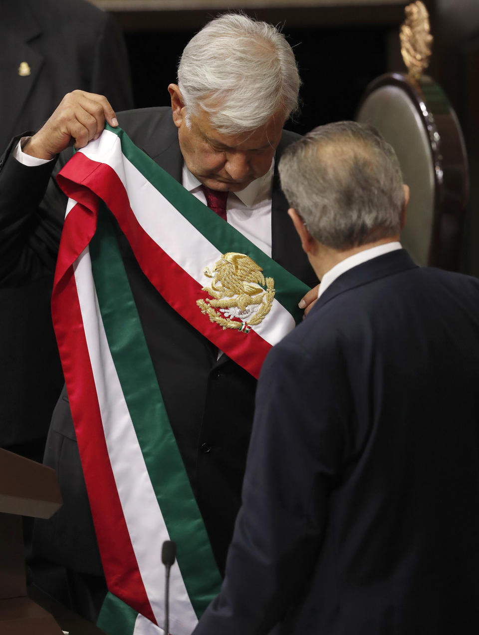 Mexico's new President Andres Manuel Lopez Obrador holds the presidential sash after taking the oath of office at the National Congress in Mexico City, on Saturday, Dec. 1, 2018. Lopez Obrador was sworn in Saturday as Mexico's first leftist president in over 70 years. (AP Photo/Marco Ugarte)