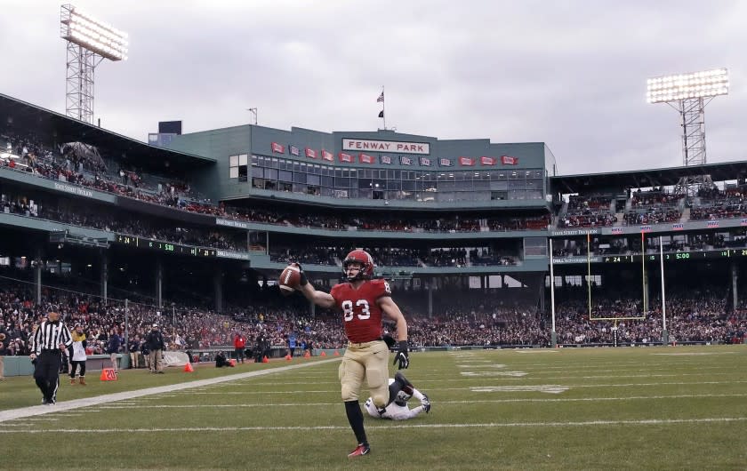 FILE - In this Nov. 17, 2018, file photo, Harvard wide receiver Jack Cook (83) raises the ball after crossing the goal line for a touchdown against Yale during the second half of an NCAA college football game at Fenway Park in Boston. The Ivy League has canceled all fall sports because of the coronavirus pandemic. (AP Photo/Charles Krupa, File)