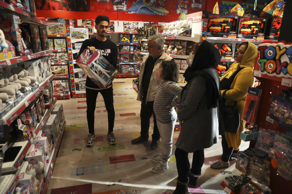 A shopkeeper explains on a toy for customers at a store in Bamland shopping mall, in Western Tehran, Iran, Sunday, March 15, 2020. Many people in Tehran shrugged off warnings over the new coronavirus as authorities complained that most people in the capital are not treating the crisis seriously enough. (AP Photo/Vahid Salemi)
