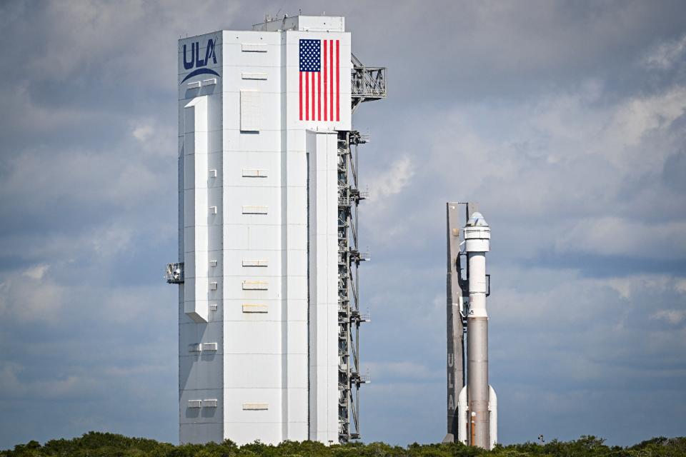 eine Rakete neben einem hohen Gebäude mit Wolken im Hintergrund