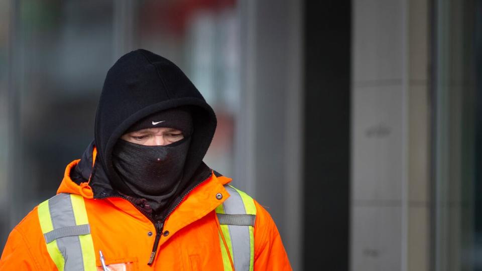 A man in high-visibility work gear walks outside in Windsor during frigid temperatures in January 2024.