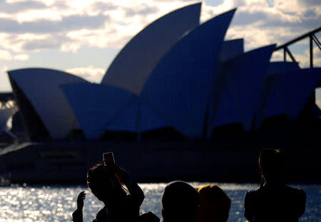 Chinese and Malaysian tourists take photographs of the Sydney Opera House from a viewing area located on Sydney Harbour, Australia. REUTERS/David Gray