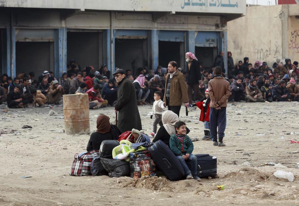 Displaced Iraqis, who fled fighting between Iraqi security forces and Islamic State militants, waiting at the gathering point to be taken for a camp for internally displaced people, in Bartella, around 19 miles (kilometers), from Mosul, Iraq, Saturday, Dec 31, 2016. (AP Photo/ Khalid Mohammed)