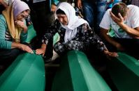 People mourn over coffins of their relatives in Srebrenica on July 9, 2015 where 136 bodies found in mass grave sites in eastern Bosnia will be reburied on 20th anniversary of the Srebrenica massacre