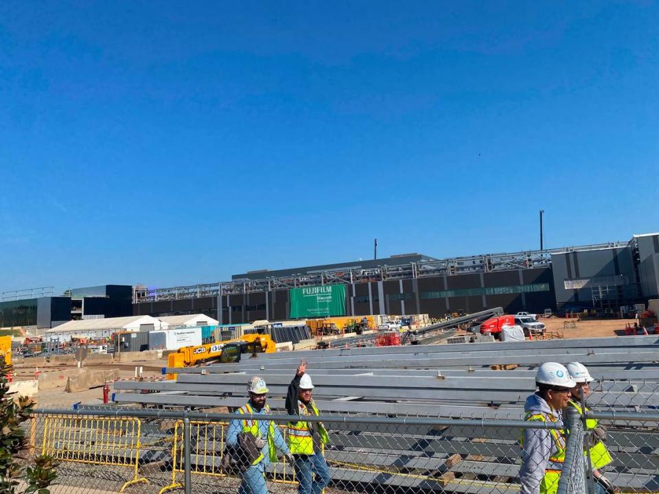 Workers walk by the Fujifilm construction site in Holly Springs, NC.