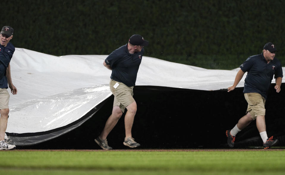 Grounds crew workers put the tarp onto the field during the third rain delay in the baseball game between the Milwaukee Brewers and the Minnesota Twins on Tuesday, July 12, 2022, in Minneapolis. (AP Photo/Jim Mone)