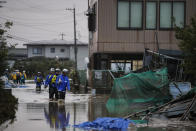 Search and rescue team members wade through floodwaters Monday, Oct. 14, 2019, in Hoyasu, Japan. Rescue crews in Japan dug through mudslides and searched near swollen rivers Monday as they looked for those missing from a typhoon that left as many as 36 dead and caused serious damage in central and northern Japan. (AP Photo/Jae C. Hong)