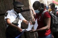 An employee checks the documents of a migrant from Haiti as he lines up to regularise his migratory situation outside of the Mexican Commission for Aid to Refugees (COMAR), in Mexico City